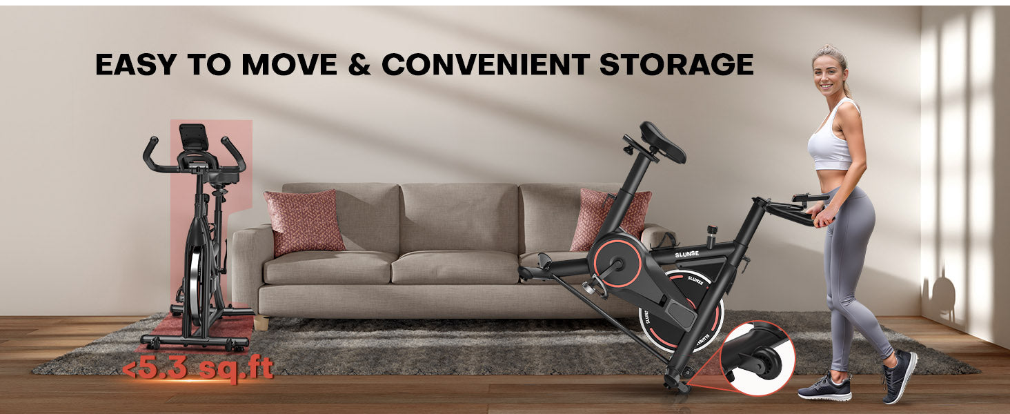 Bicicleta estática con una mujer de pie junto a ella, colocada sobre un piso de madera en un entorno de sala de estar.